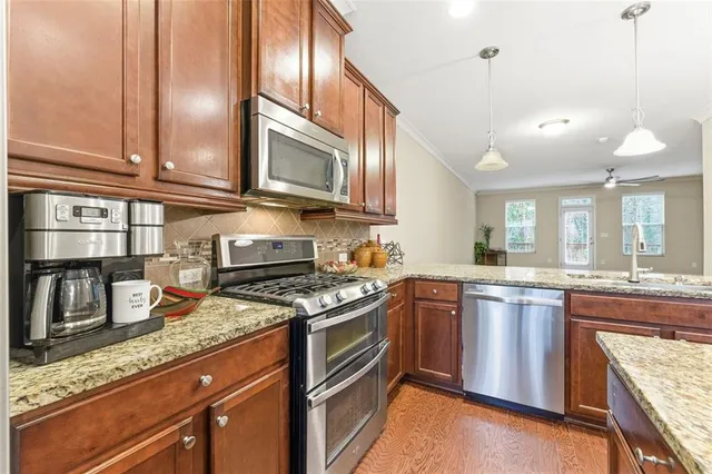 a kitchen with stainless steel appliances granite countertop a stove a sink and a microwave