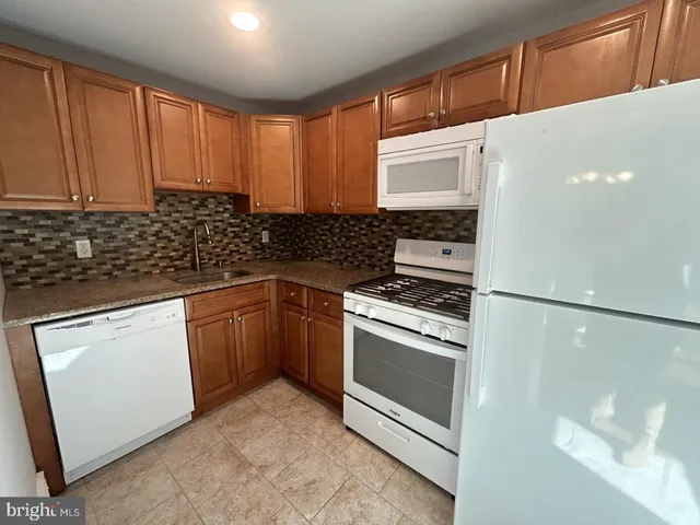 a kitchen with granite countertop a refrigerator stove and sink