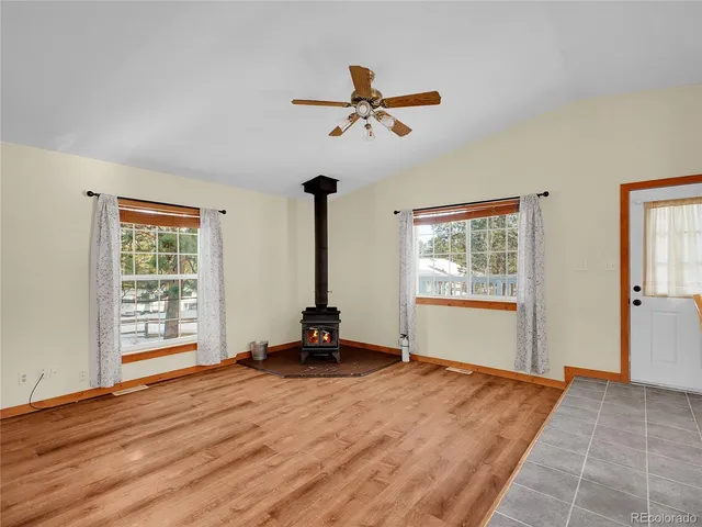 a view of a room with wooden floor a ceiling fan and windows