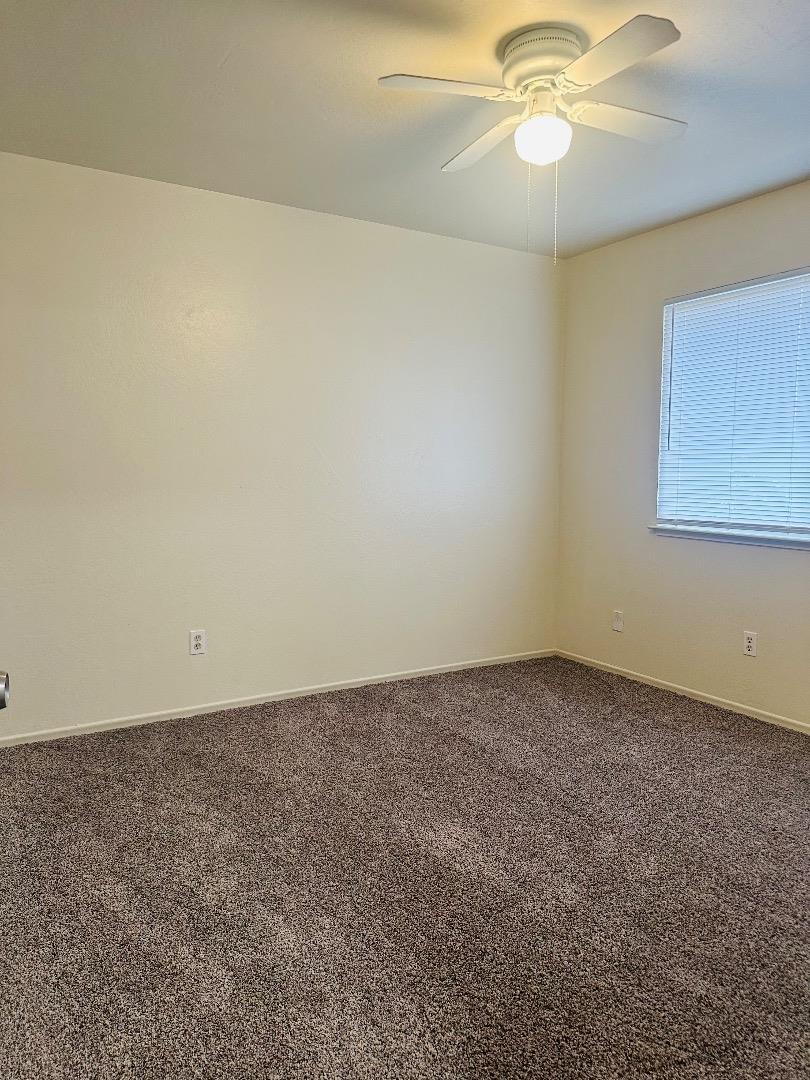 1707 West Swain Road, Unit 10 Stockton, CA 95207 - Photo 5 of 18 an empty room with a chandelier fan and table