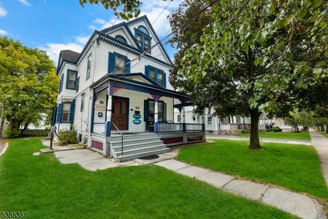 a view of a white house with a big yard and large trees