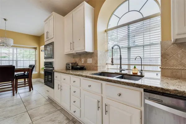 a kitchen with granite countertop a sink a window appliances and cabinets