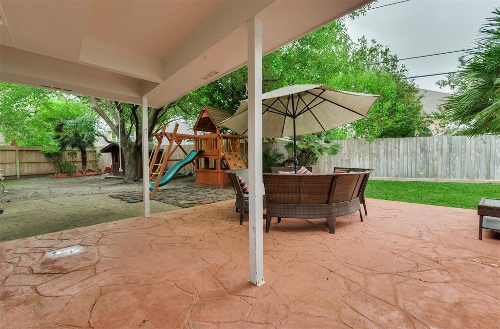 14103 Heatherhill Place Houston, TX 77077 - Photo 37 of 47 a view of a backyard with table and chairs under an umbrella with a small yard