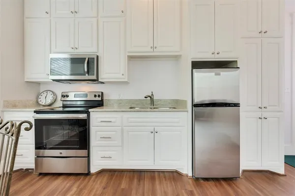 a kitchen with stainless steel appliances granite countertop a refrigerator stove and white cabinets