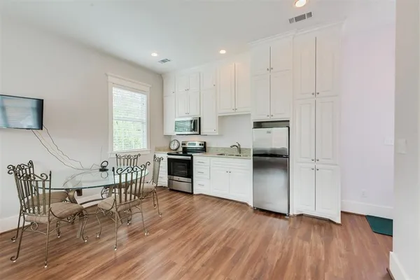 a kitchen with granite countertop wooden floors stainless steel appliances and white cabinets