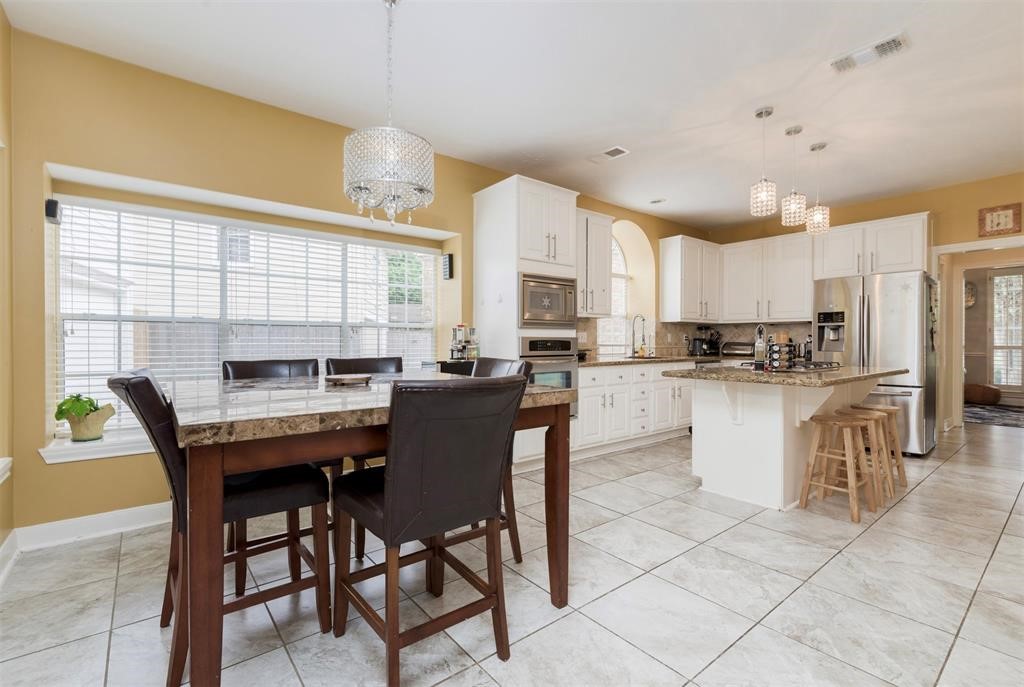 14103 Heatherhill Place Houston, TX 77077 - Photo 8 of 47 a kitchen with stainless steel appliances granite countertop a stove a sink a dining table and chairs