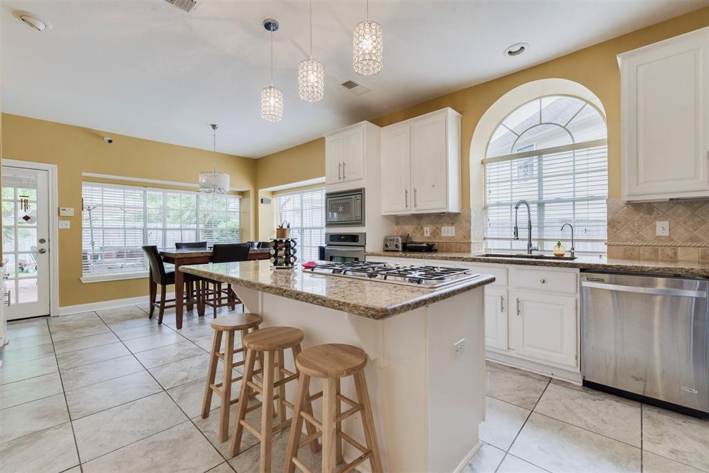 14103 Heatherhill Place Houston, TX 77077 - Photo 10 of 47 a kitchen with stainless steel appliances granite countertop a stove top oven a sink a dining table and chairs with a large window