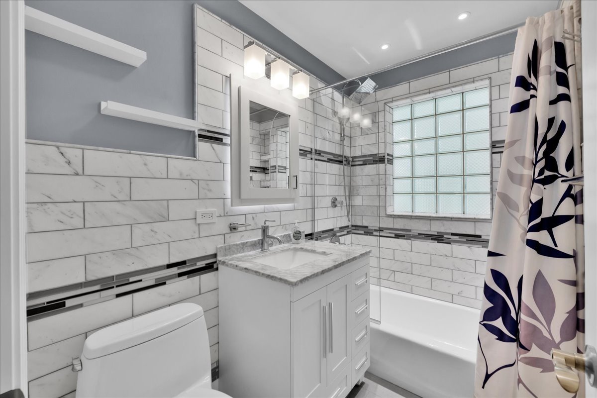 1427 Busse Road Mount Prospect, IL 60056 - Photo 31 of 38 a bathroom with a granite countertop sink a toilet and shower