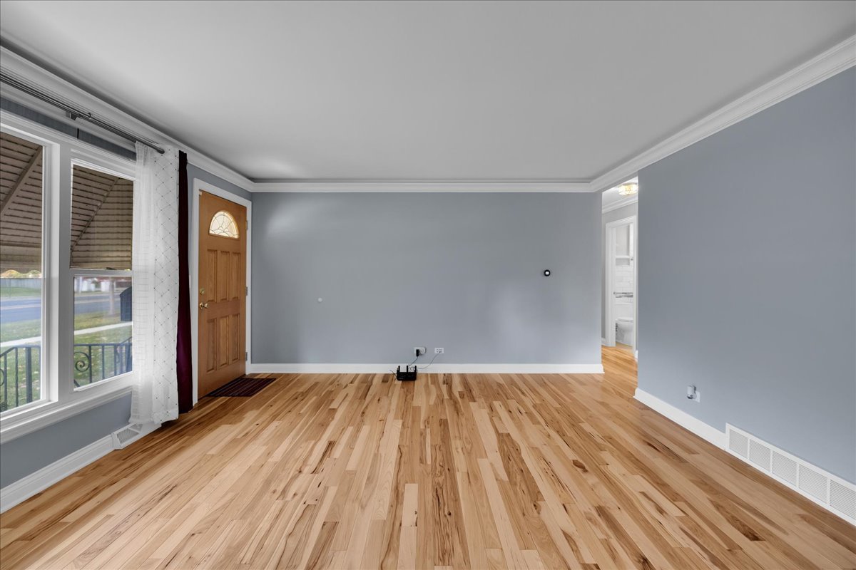 1427 Busse Road Mount Prospect, IL 60056 - Photo 5 of 38 a view of an empty room with wooden floor and a window
