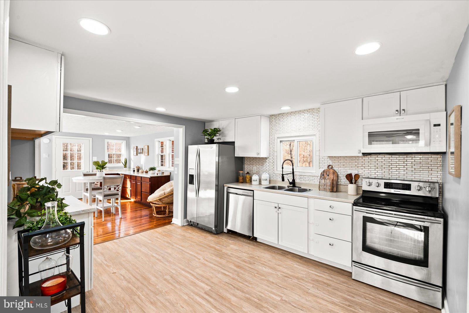 27 Truslow Road Fredericksburg, VA 22405 - Photo 9 of 35 a kitchen with stainless steel appliances kitchen island granite countertop a stove top oven a sink a dining table and chairs with wooden floor