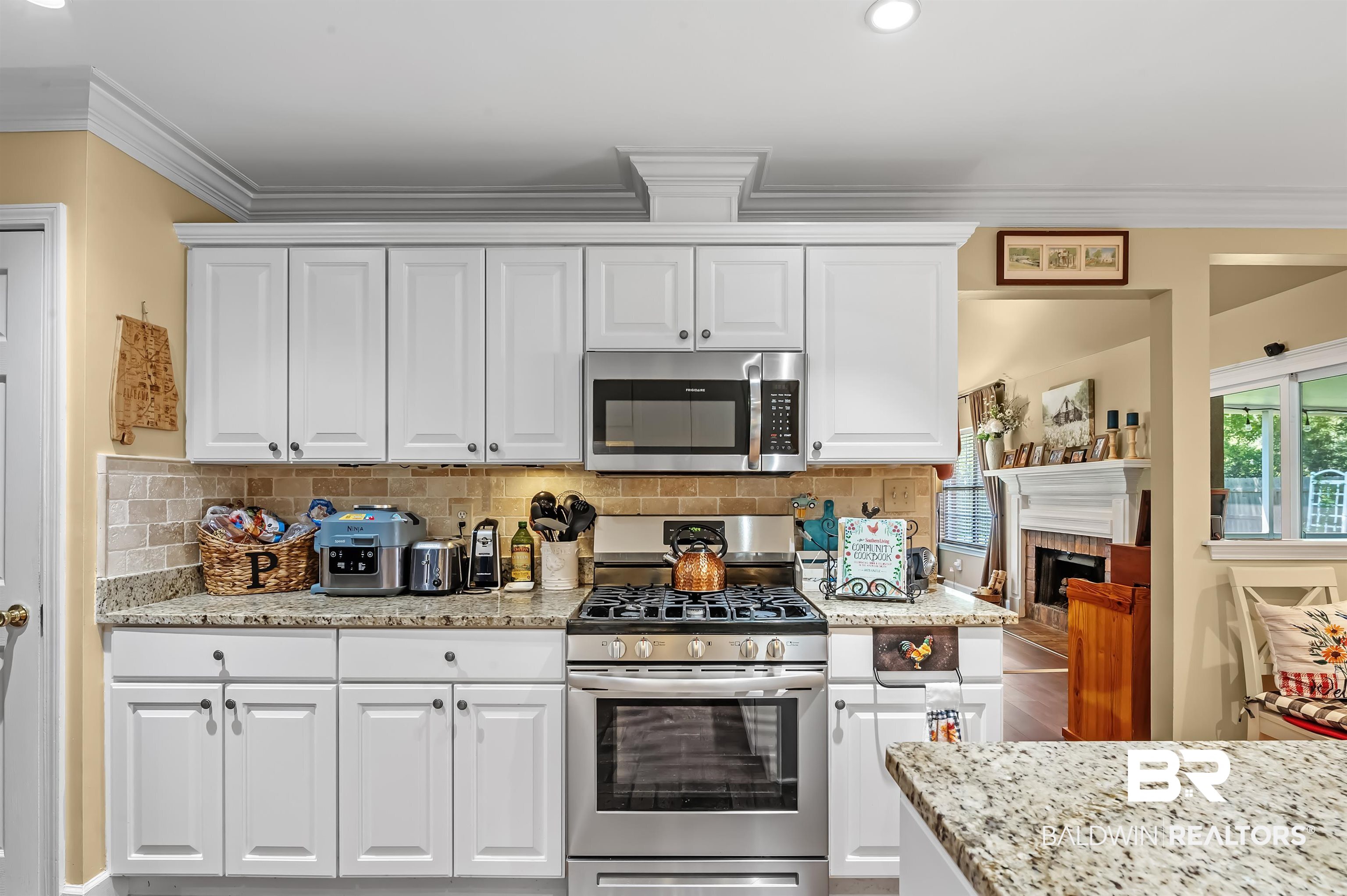 9901 Glover Court Fairhope, AL 36532 - Photo 15 of 52 Kitchen featuring white cabinetry, appliances with stainless steel finishes, a fireplace, and crown molding