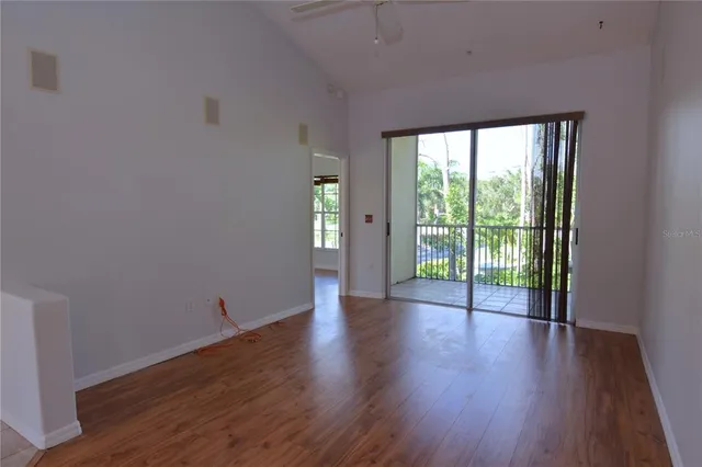 a view of an empty room with wooden floor and a window