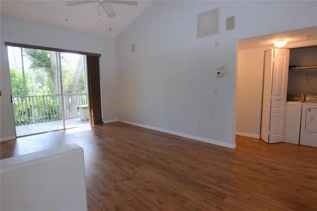 a view of empty room with wooden floor and fan