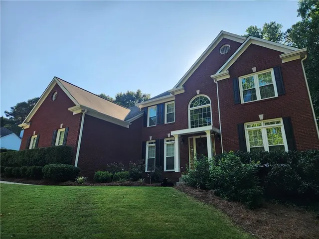 a view of house with a big yard and potted plants