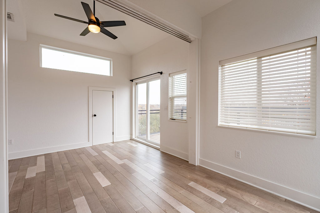 2016 Peoples Street Austin, TX 78702 - Photo 20 of 28 Unfurnished room featuring ceiling fan, plenty of natural light, light wood-type flooring, and a high ceiling