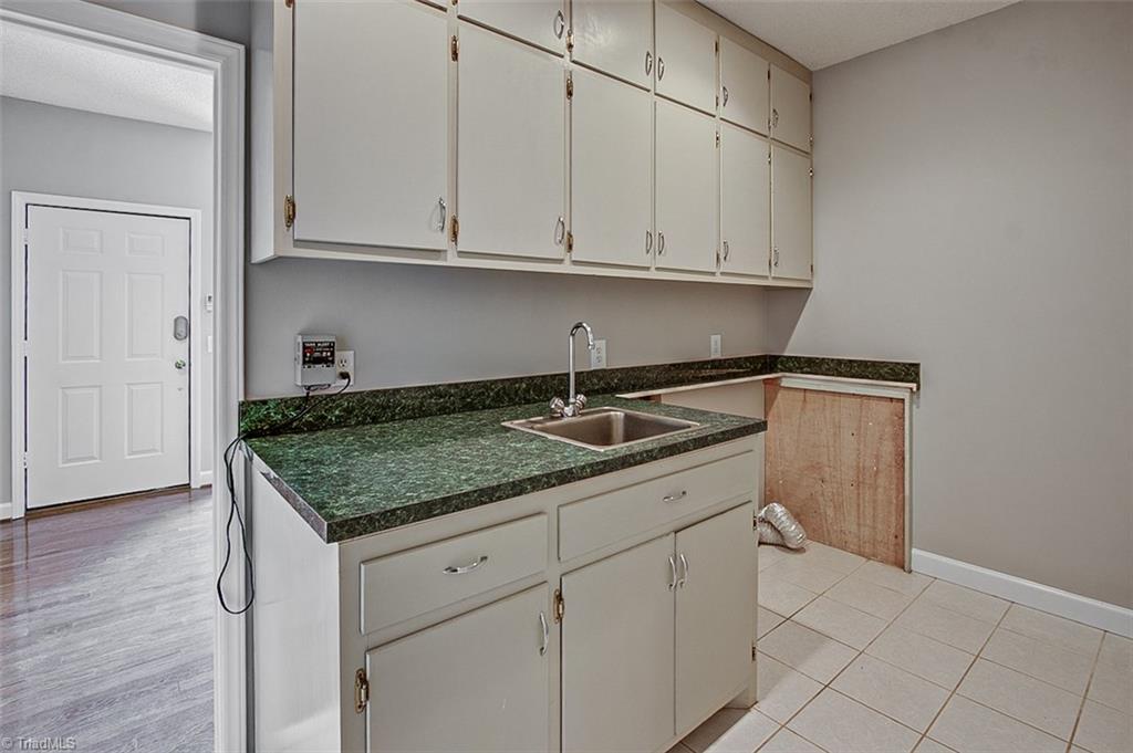 9015 Racine Road Pleasant Garden, NC 27313 - Photo 24 of 30 Laundry room w/ceramic til floor, utility sink & storage cabinets