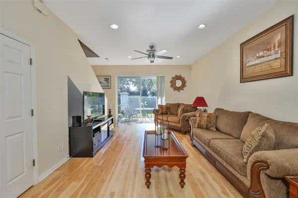 a living room with furniture kitchen view and a wooden floor