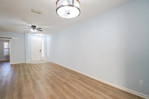 a view of a room with wooden floor and a ceiling fan