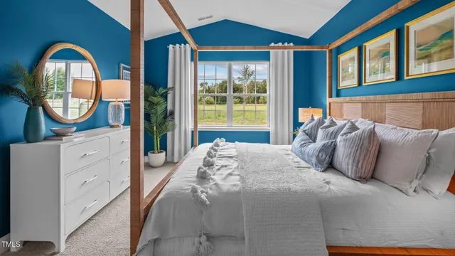 a bedroom with a bed a mirror on dresser and a large window