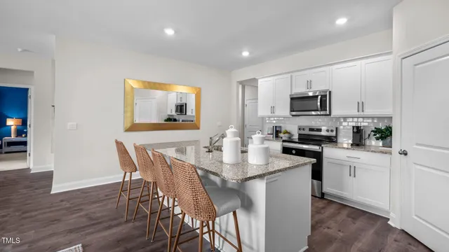 a kitchen with stainless steel appliances granite countertop a stove a sink a microwave a dining table and chairs