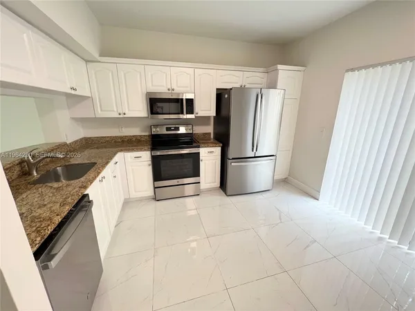 a kitchen with stainless steel appliances granite countertop a refrigerator stove top oven and sink