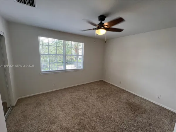 an empty room with windows and fan