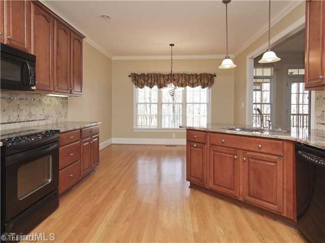 5411 Effieham Street Oak Ridge, NC 27310 - Photo 4 of 16 Kitchen. Another view of the kitchen towards the rear of the home and the breakfast area which looks out toward the rear yard and woods.