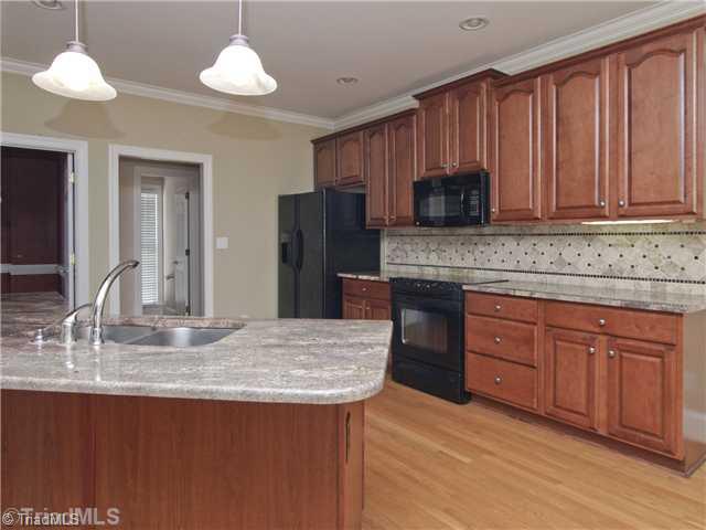 5411 Effieham Street Oak Ridge, NC 27310 - Photo 5 of 16 Kitchen. Kitchen has tons of storage and loads of counter space. Cabinets feature a built in trash can right by sink where you need it! Walk in pantry is just to the right in this photo.