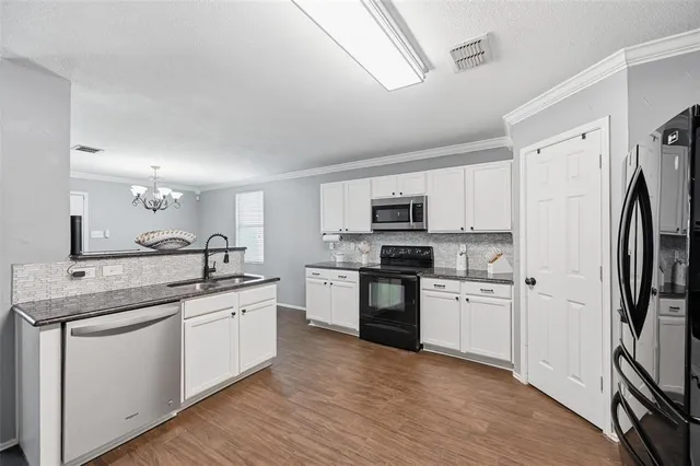 a kitchen with stainless steel appliances granite countertop wooden floors and view living room