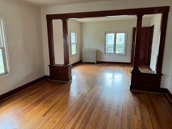 a view of an empty room with wooden floor and a window