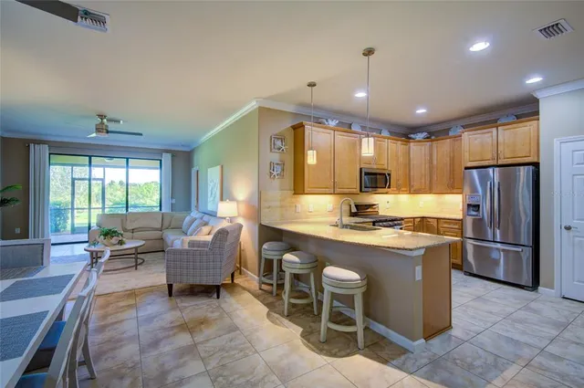 a large kitchen with kitchen island a sink a center island stainless steel appliances and a window