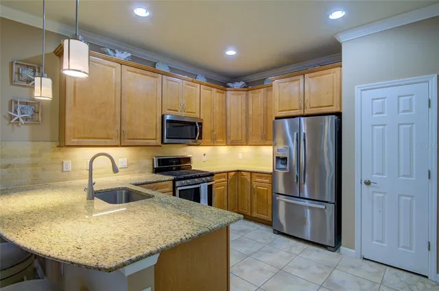 a kitchen with stainless steel appliances granite countertop a refrigerator a stove a sink and a microwave