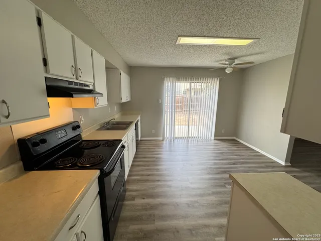 a kitchen with granite countertop a stove and white cabinets