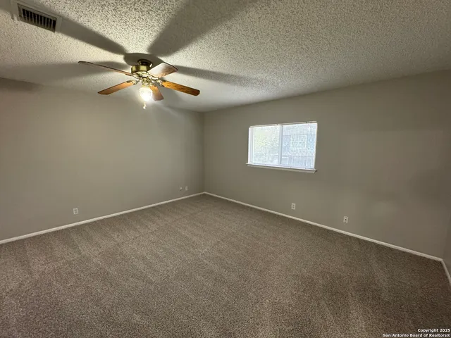 an empty room with a window and a fan