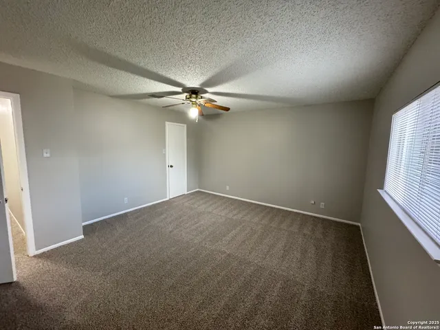 an empty room with a window and chandelier fan
