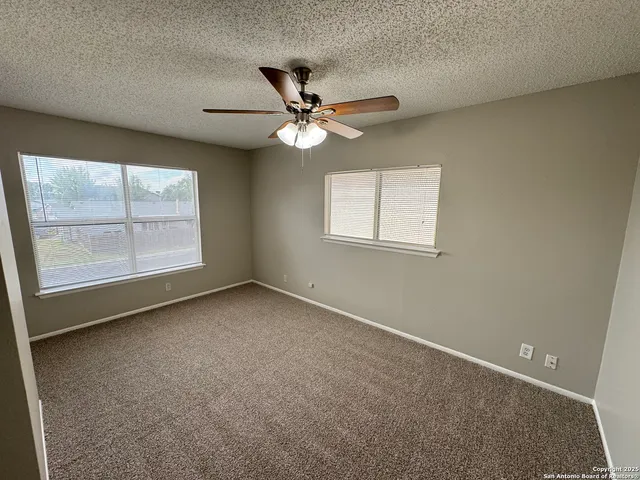 an empty room with windows and fan