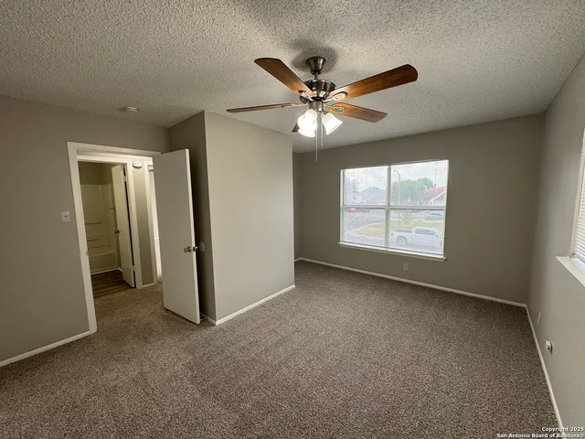 an empty room with windows and fan