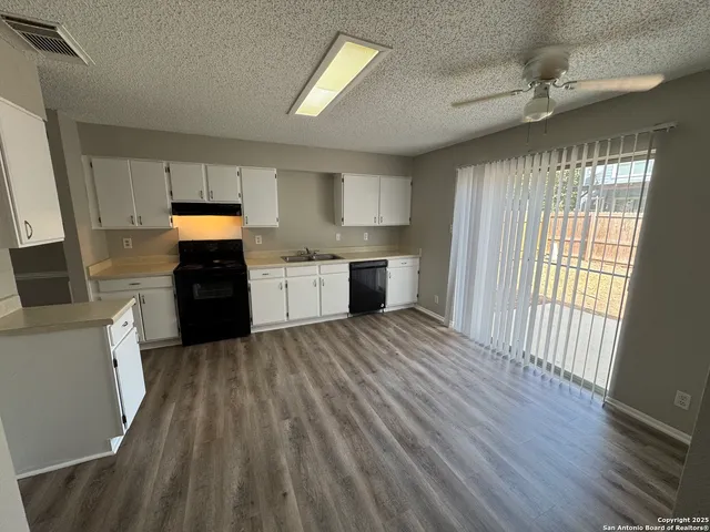 a large kitchen with cabinets wooden floor and stainless steel appliances