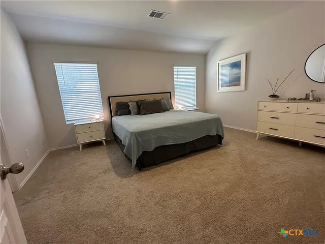 a spacious bedroom with a bed and a dresser