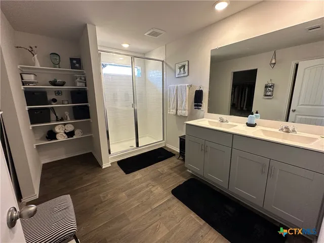 a spacious bathroom with a double vanity sink a mirror and a shower