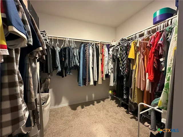 a view of walk in closet with clothes and shoes