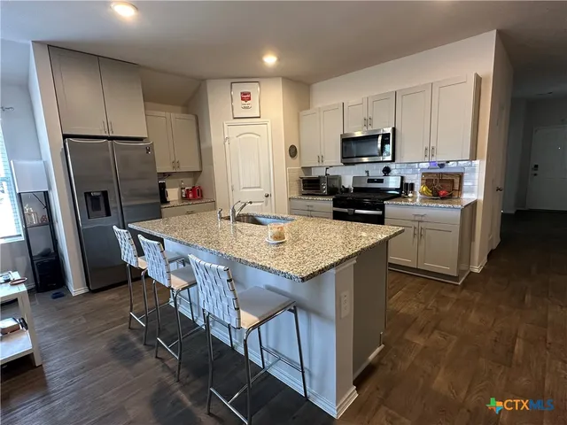 a kitchen with kitchen island a wooden floor and a refrigerator