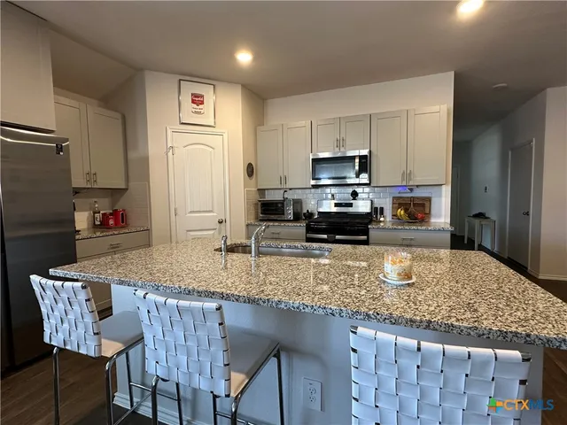 a kitchen with granite countertop a stove a sink a dining table and chairs