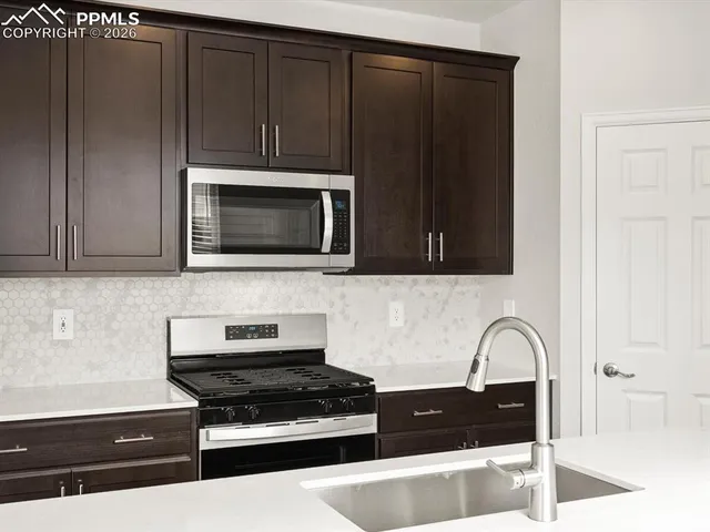 a kitchen with granite countertop white cabinets and black appliances