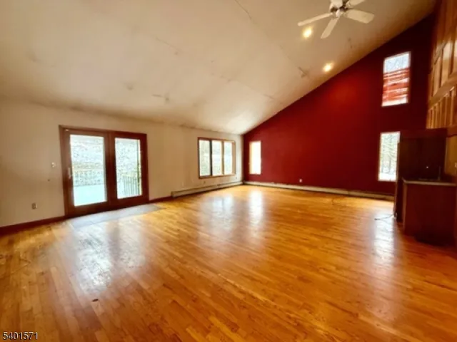 a view of an empty room with window and wooden floor
