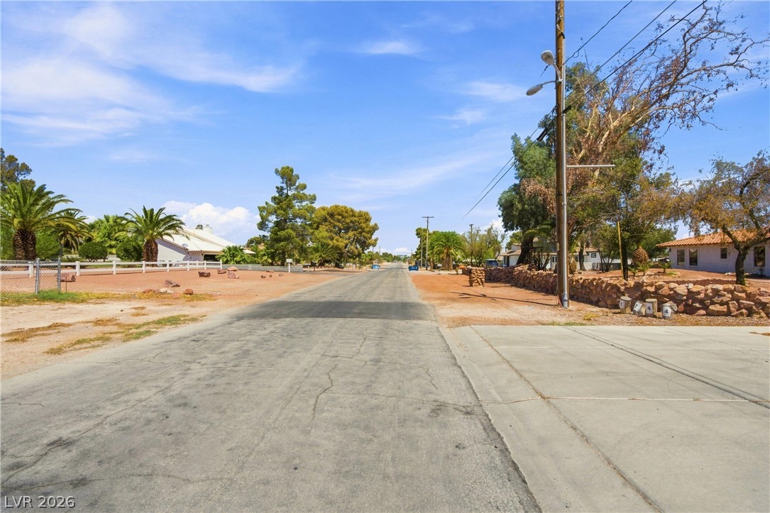 7744 Rancho Destino Road Las Vegas, NV 89123 - Photo 7 of 48 A paved residential street sits under open blue skies bordered by desert landscaping and fencing.
