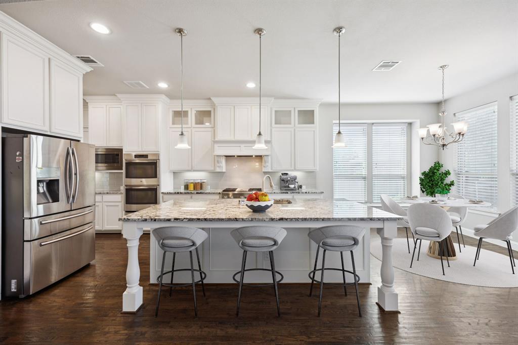 965 Touchstone Road Frisco, TX 75036 - Photo 7 of 36 a kitchen with stainless steel appliances granite countertop a stove a refrigerator a kitchen island a dining table and chairs with wooden floor