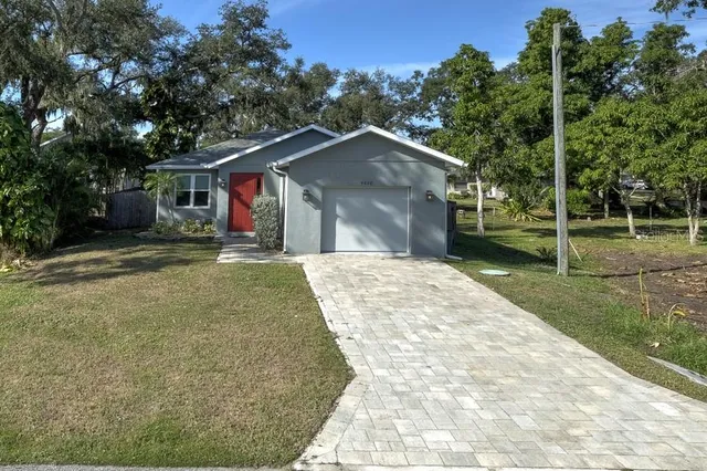 a view of a house with a yard and large trees