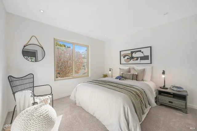 a bedroom with a bed a window and painting on the wall