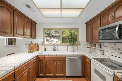 a kitchen with stainless steel appliances granite countertop a sink a stove cabinets and wooden floor
